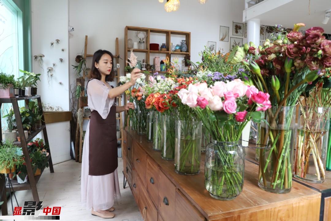 王黎媛是一名河南姑娘，在昆明念完大學(xué)后，就再也舍不下春城的藍天陽光、青山碧水，更舍不下這里的四時繁花，于是就干脆留了下來，成了一名媒體人。2017年的時候又毅然辭去工作，創(chuàng)業(yè)開起了花店，成了都市里的一名“花房姑娘”。圖為王黎媛在自己的花店中整理鮮花。新華網(wǎng) 周亞平/攝 念新洪/文